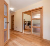 A hallway of a family house with wooden doors and a floor with a wooden decor.