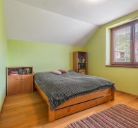 A bedroom in a family house with a wood-patterned floor and a large window.