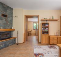 A fireplace with a stone cladding in the living room of a family house with wooden furniture and tiles.