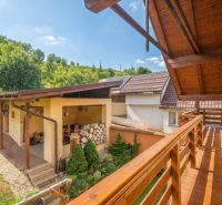 The balcony of a family house in Horná Lehota, wooden railing, garden, and shed.