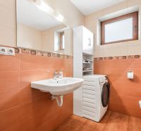 A bathroom in a family house with orange tiles and a washing machine.