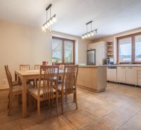 A kitchen in a family house with a dining table, wooden decor, and modern appliances.