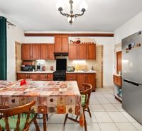 A kitchen in a family house with a dining table, wooden cabinets, and a refrigerator.