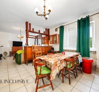 Dining room in a family house with corner cabinets, cream tiles, and green curtains.