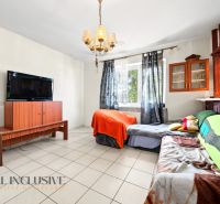 Living room with a TV, sofa, and cabinet in a family house, light through curtains.