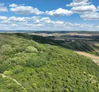 Hilly green terrain and extensive agricultural and forest lands in Tornaľa, on a clear day.