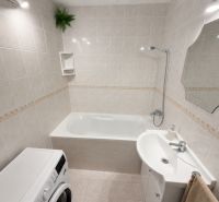 Bathroom with a bathtub, sink, and washing machine in a 3-room apartment, bright tiles.