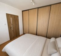 The interior of a bedroom in a three-room apartment with a wooden decor floor and a large wardrobe.