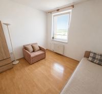 A room in a 3-room apartment with a wooden decor floor, a sofa, and an armchair.