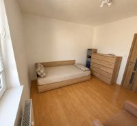 A room in a 3-room apartment with a bed, a dresser, and a floor with a wooden decor.