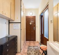 Entrance hall of a one-room apartment with furniture and decorations on a tiled floor.