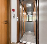 An open elevator and doors in a building, floor with wooden decor.