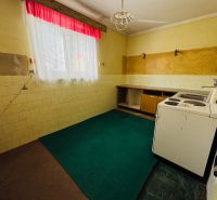 A kitchen in a 2-room apartment with a linoleum floor and a window with curtains.