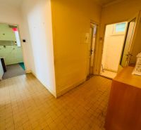 Hallway of a 2-room apartment with tiles and several open doors.