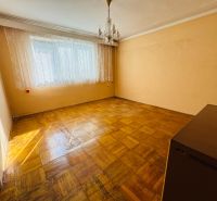 A room in a 2-room apartment with a crystal chandelier and a wooden decor floor.