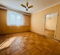 A room in a 2-room apartment with a wood-patterned floor and curtains on the window.