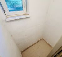 A small room with a window, white walls, and light tiles in a 2-room apartment.