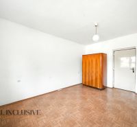 A room in a family house with white walls, a wooden decor floor, and a wooden wardrobe.