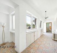 A hallway in a family house with large windows, tiled flooring, and a light fixture.