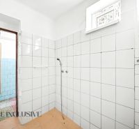 A bathroom in a family house with white tiles and a simple shower.