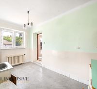 A kitchen area in a family house with a sink, green walls, and a radiator.