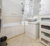 A bathroom in a 2-room apartment with a bathtub and a white sink on a cabinet.