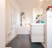 A bathroom in a 3-room apartment with a dark floor and light furniture.