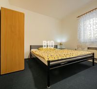 Bedroom in a family house with a metal bed, wardrobe, and patterned curtain.