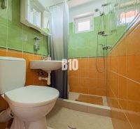 A bathroom in a family house with orange and green tiles and a shower corner.