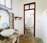 A bathroom in a family house with an interesting mosaic sink countertop and a separate toilet.