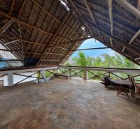 Rustic roof on the upper floor of a family house in Fumba Town with a view of palm trees.