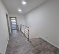 A hallway in a family house with a staircase and ceramic tiles.