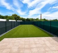 The garden of a family house in Trnava with a lawn and a paved terrace under a blue sky.