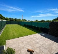 The terrace of a family house in Trnava with paving and green lawn, a dog is resting.