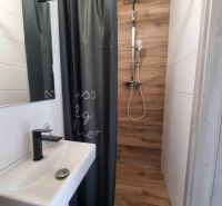 A bathroom in a family house with a wooden decor shower corner and a curtain.