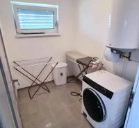 Laundry room in a family house with a washing machine and dryer, floor with wooden decor.