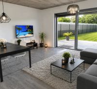 A living room in a family house with a wooden decor floor and a view of the garden.