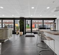 Interior of commercial space with a kitchen counter, bar stools, and large glass doors.