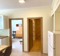 Interior of a 3-room apartment with a wooden decor floor, chairs, and a built-in wardrobe.