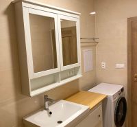 Bathroom in a 3-room apartment with a sink, mirror, and washing machine, ceramic tiles.