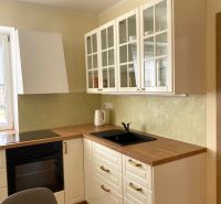 A kitchen in a 3-room apartment with white cabinets and a wood-patterned floor.