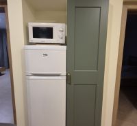 Microwave and refrigerator in the kitchen of a 3-room apartment with a wooden decor floor.
