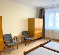 A room in a three-room apartment with a wooden decor floor, two armchairs, and a wardrobe.
