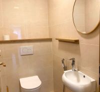 A bathroom in a 3-room apartment with beige tiles and a wooden decor floor.