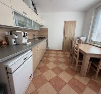 A kitchen in a 3-room apartment with a dining table, kitchen unit, and appliances.