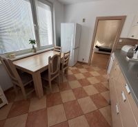 The kitchen in a 3-room apartment with a tiled floor, a dining table, and appliances.