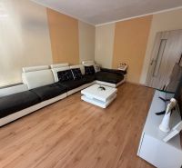 Living room with a sofa, television, and wooden decor flooring in a 3-room apartment.