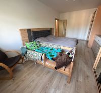 A bedroom in a 3-room apartment with a bed, an armchair, and a floor with a wooden decor.
