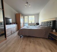 Bedroom in a 3-room apartment with a bed, wardrobe, and floor with wooden decor.