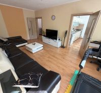 Living room in a three-room apartment with a wooden decor floor and a leather sofa.